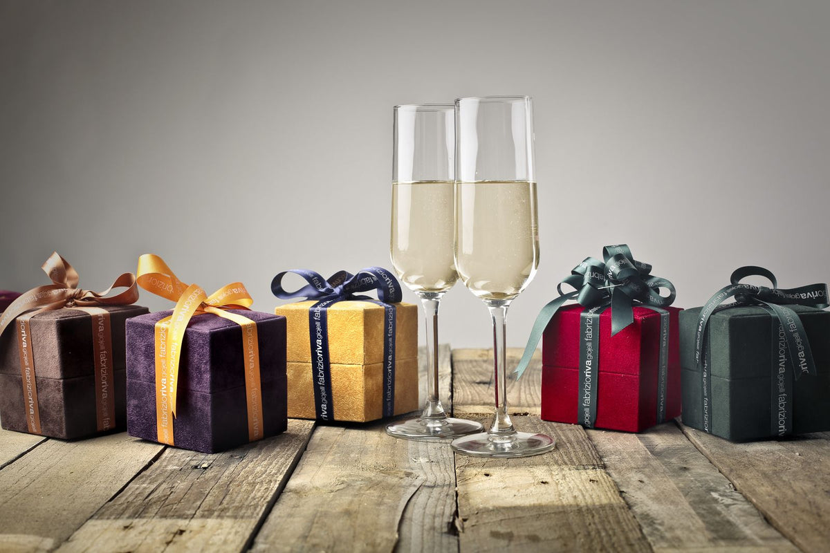 Wrapped gifts with ribbons and glasses set out on a wooden table