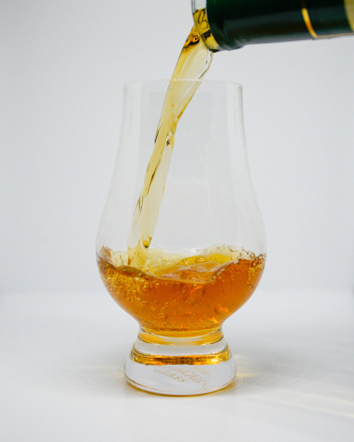 Golden whiskey being poured from a bottle into a clear glass