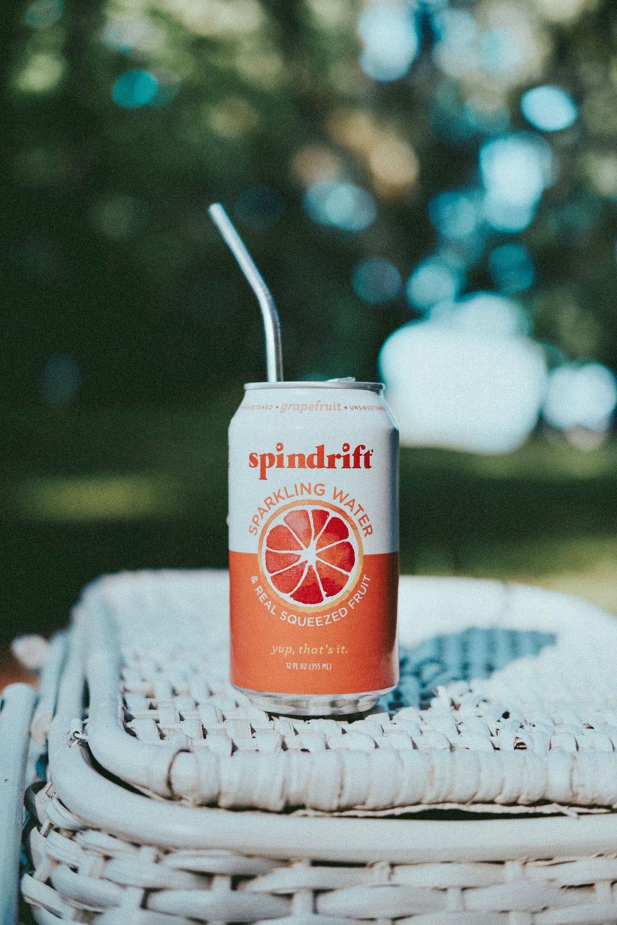 A chilled citrus drink can resting in a wicker picnic basket