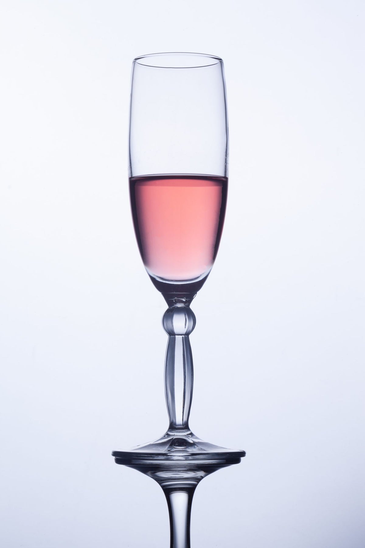 A flute of pink sparkling wine catching the light at a celebration
