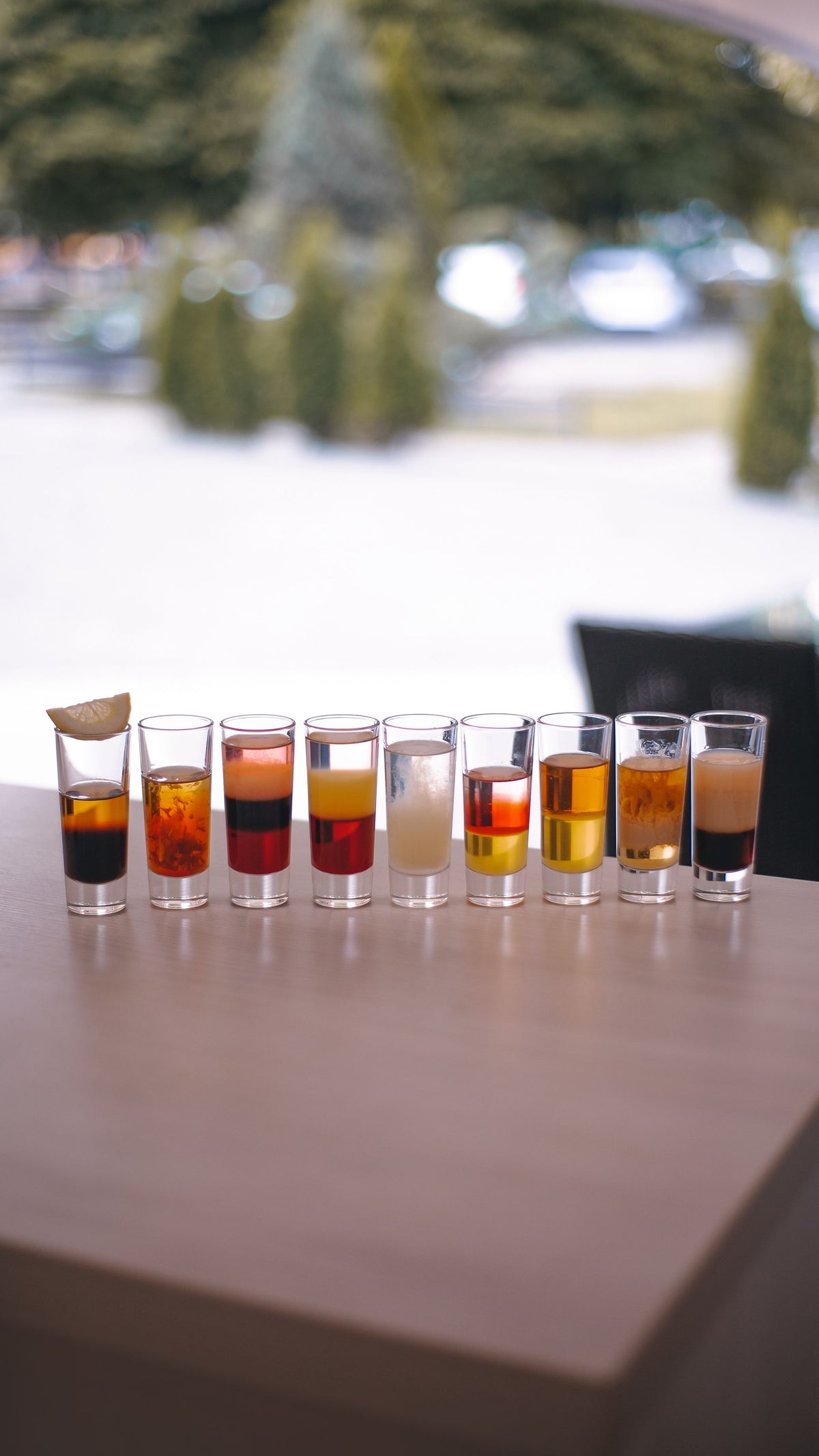 A row of layered shot glasses lined up along the edge of a bar table