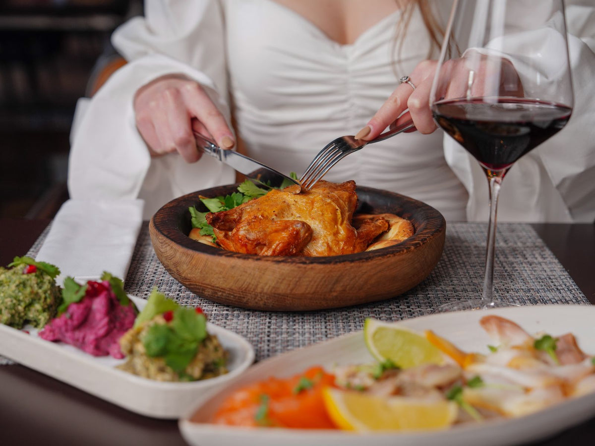 A roast chicken dinner laid out on a set table with a glass of red wine