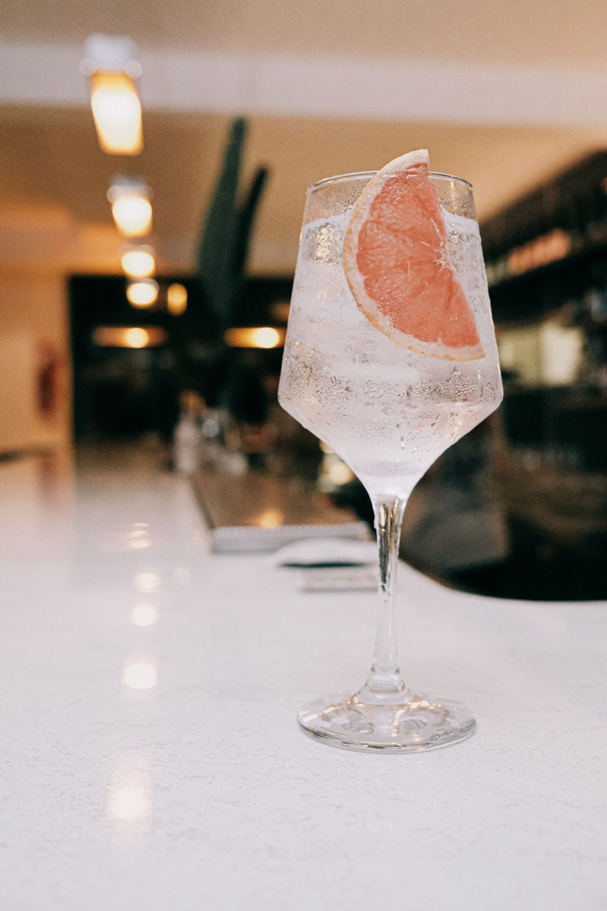 A gin and tonic with a grapefruit slice on a bar counter