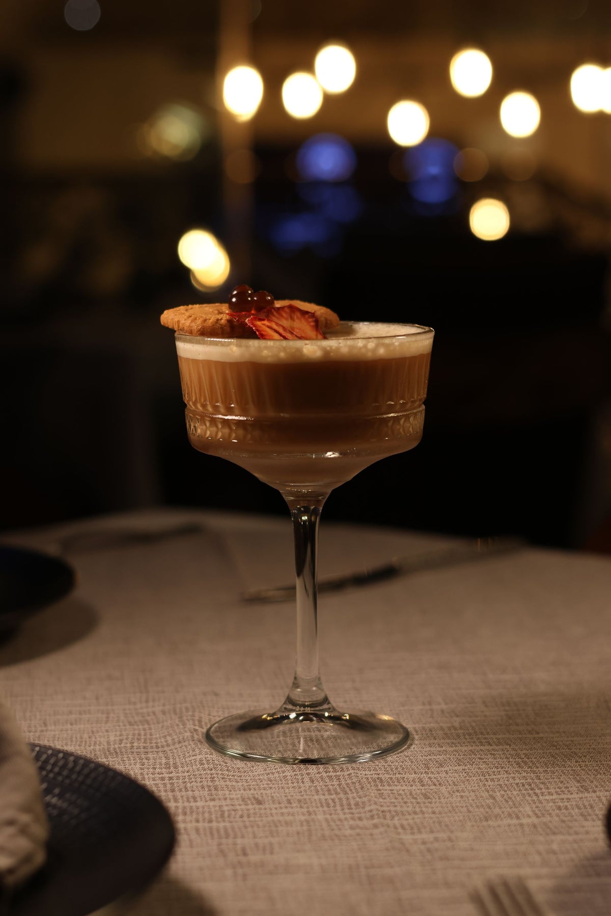 A creamy coffee liqueur drink with a cookie on a textured tablecloth