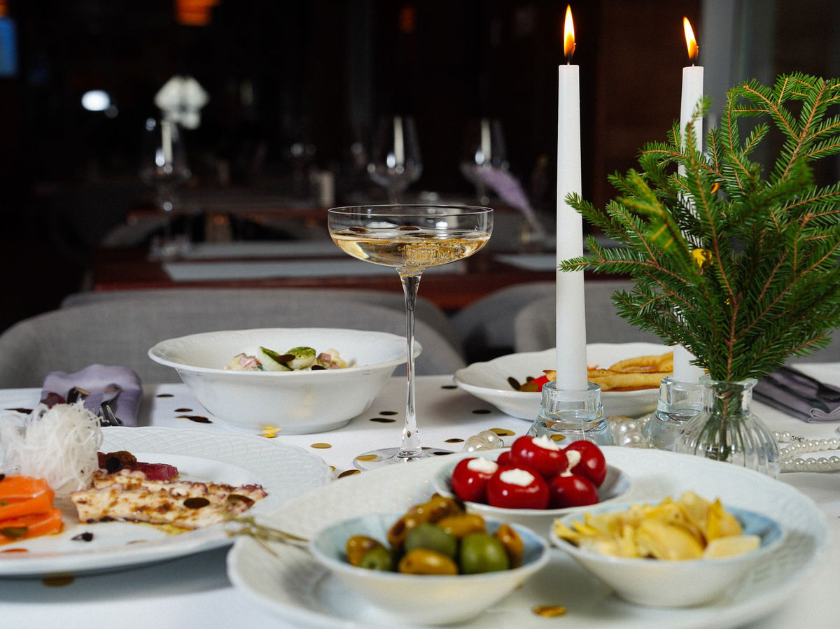 A candlelit dinner table set with glasses of sparkling wine for a festive holiday gathering