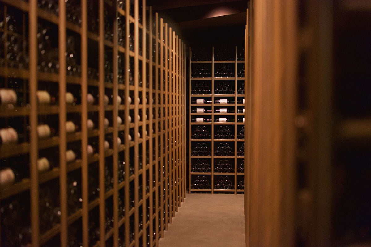 Rows of wine bottles resting in a cellar rack in Pauillac, Bordeaux
