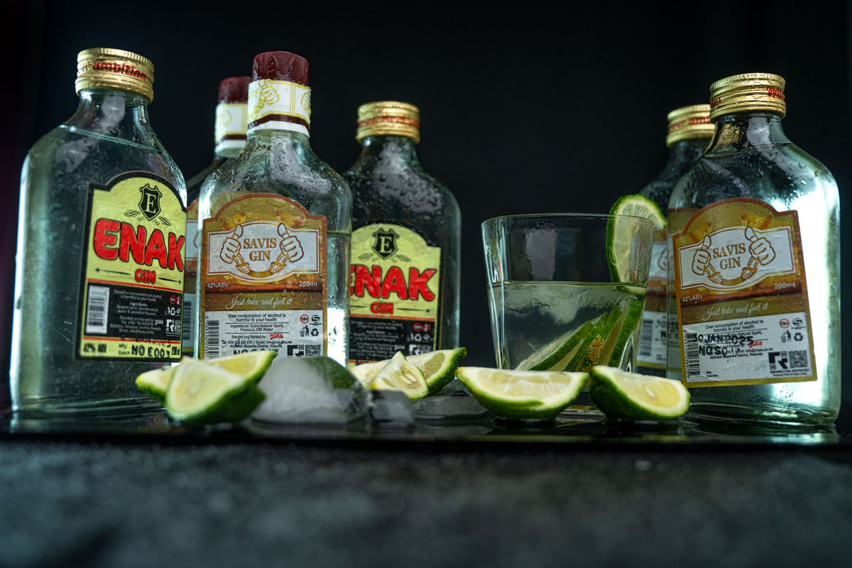 A gin cocktail with lime and ice on a dark bar top