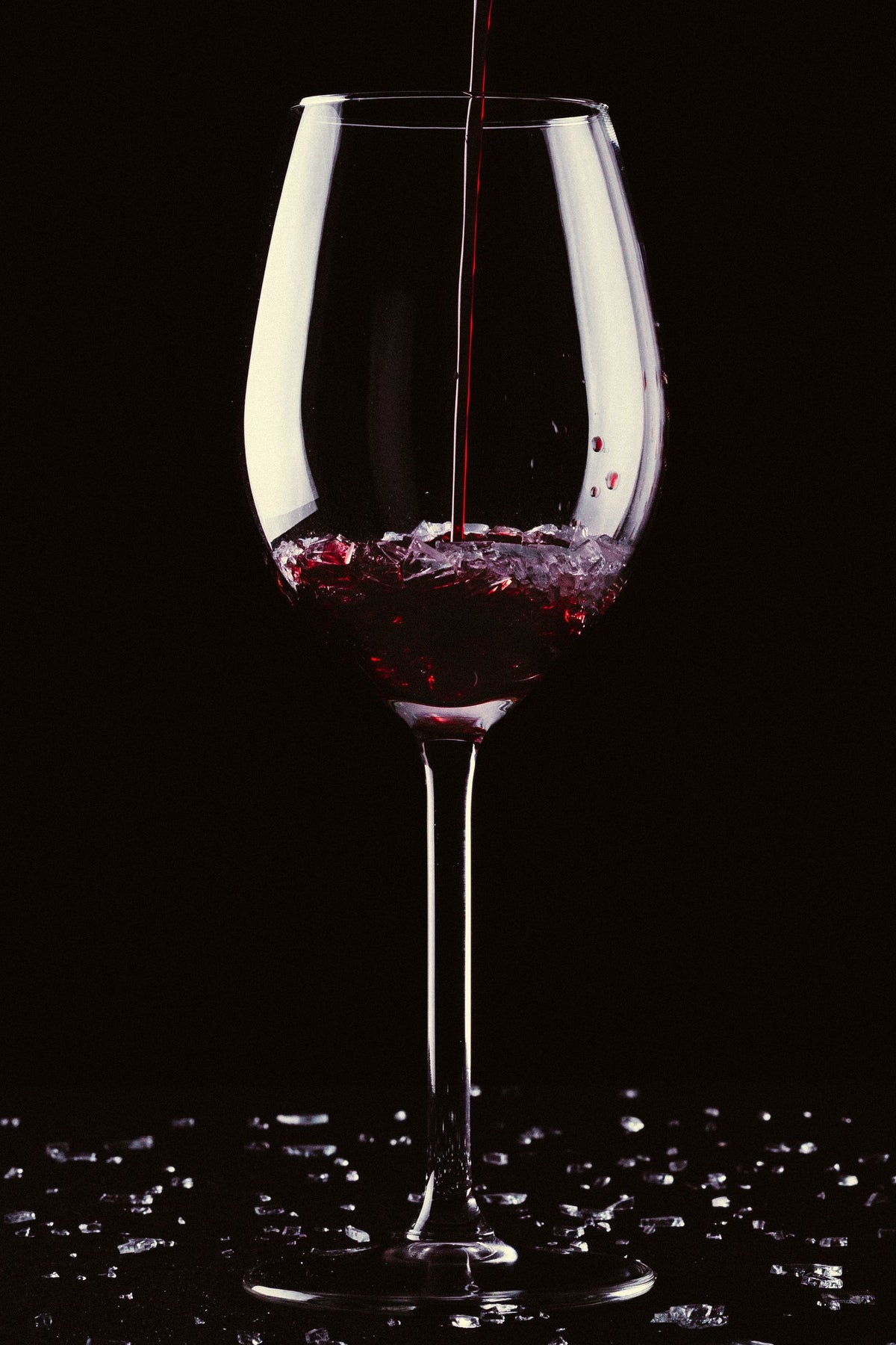 Red wine being poured into a glass against a dark background