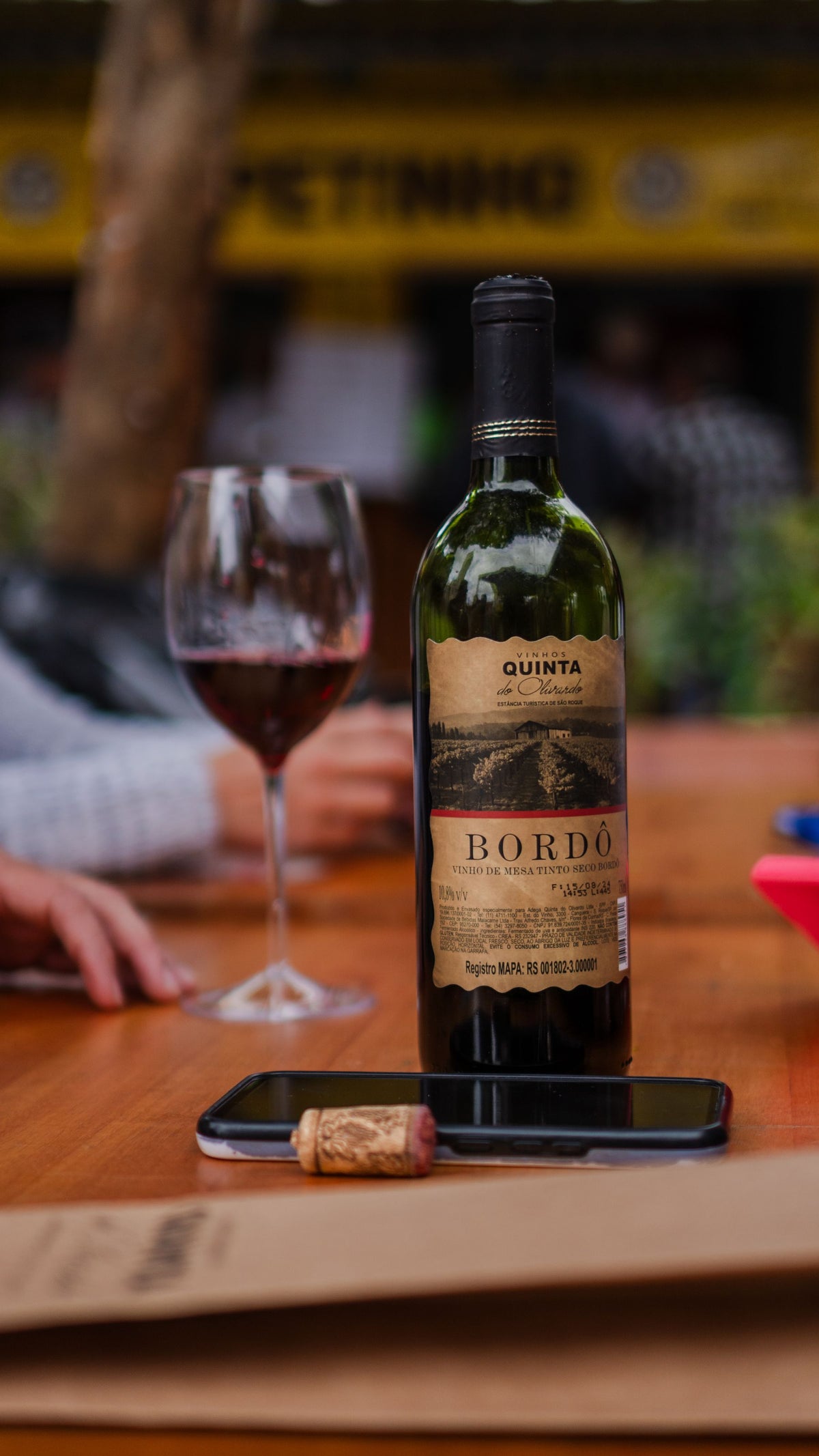 A bottle of red wine and glasses on a table set for a meal