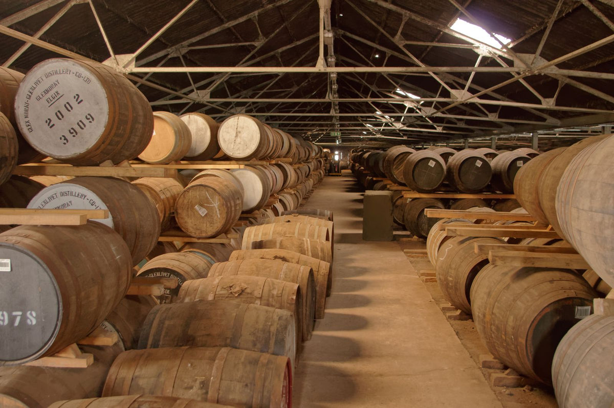 Oak barrels aging whiskey in a rustic distillery warehouse