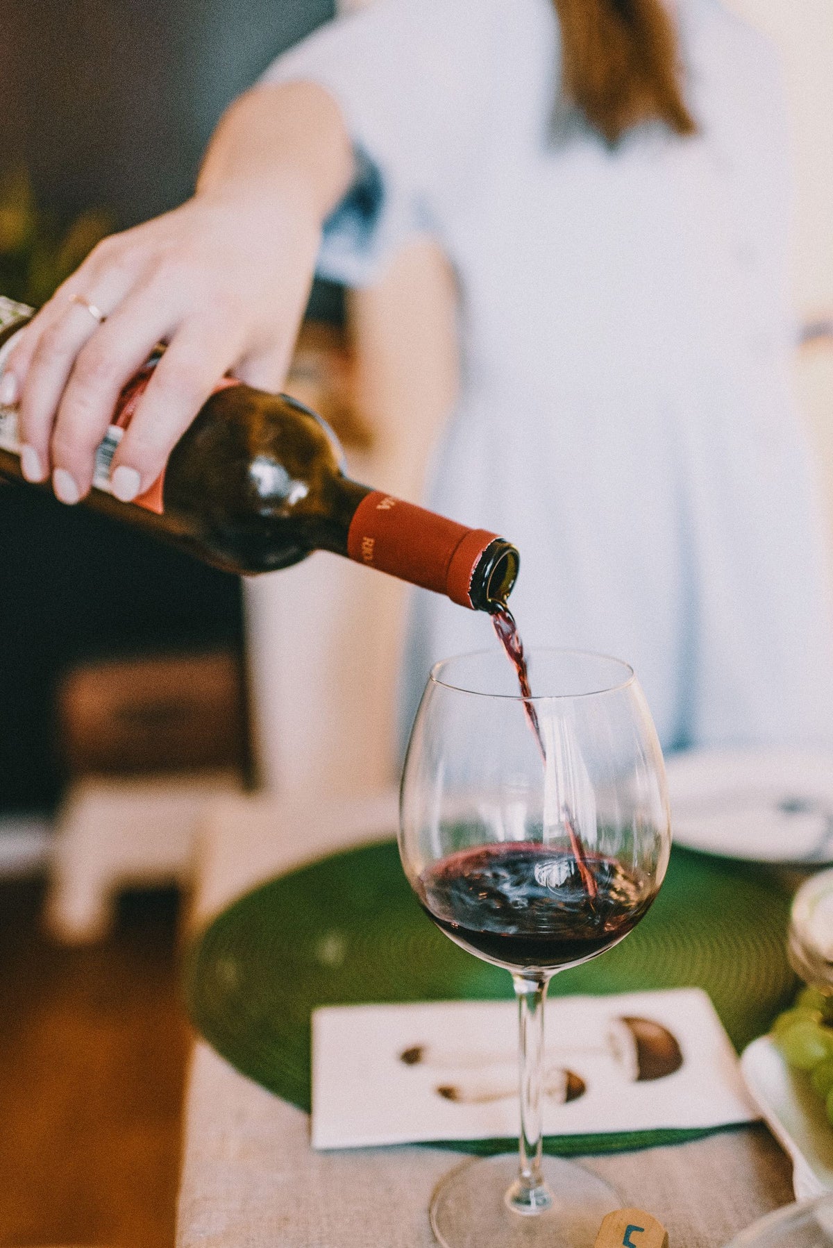 Pouring red wine into a glass at a set table