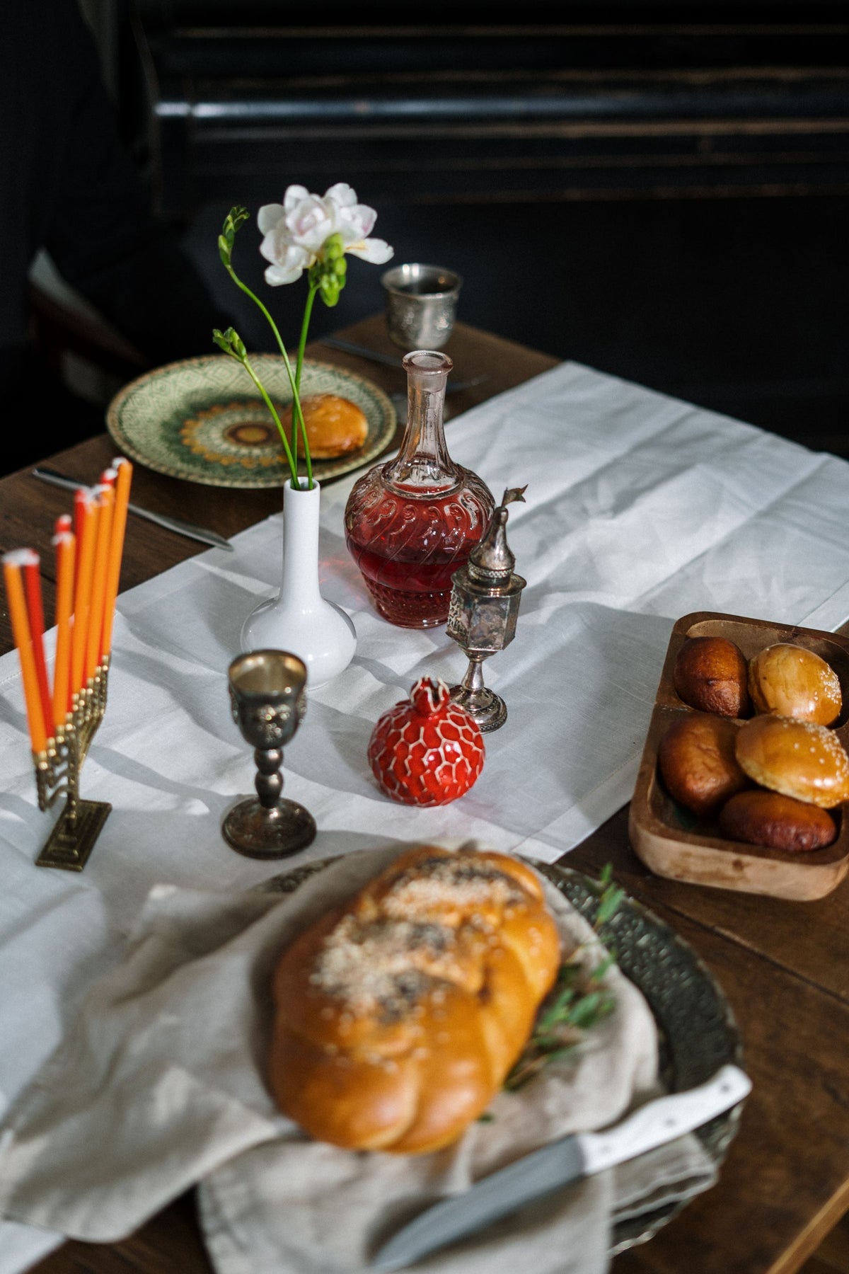 A Shabbos table set with challah, wine and lit candlesticks