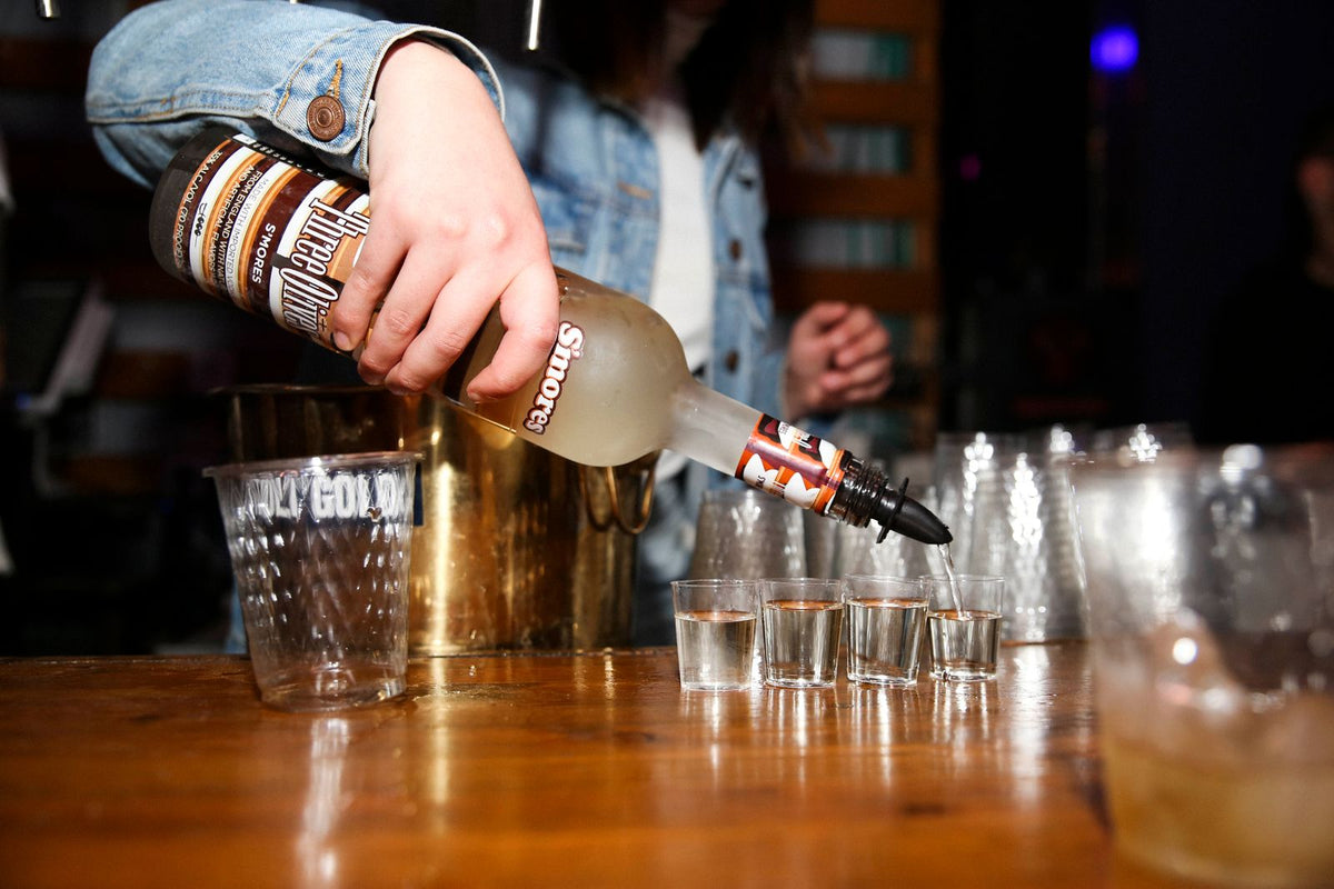 Bartender pouring spirit into shot glasses at night