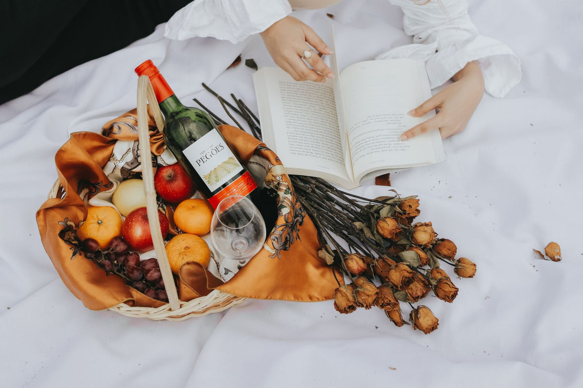 A festive picnic spread with wine, a fruit basket, and flowers
