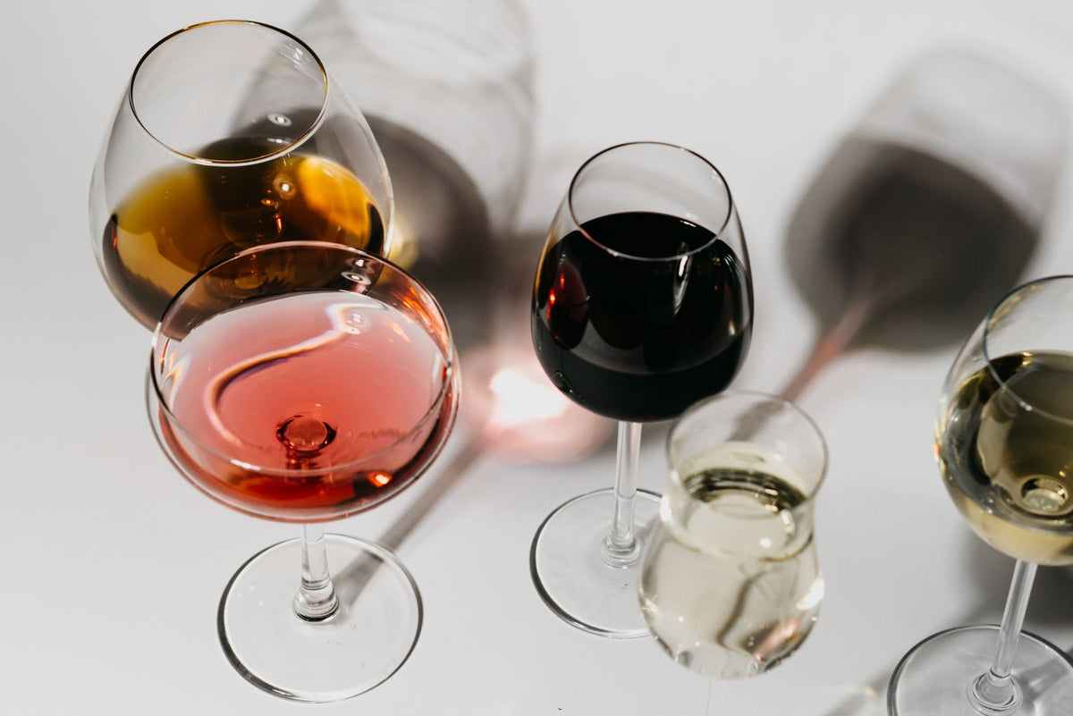 Several wine glasses filled with different wines on a pale surface