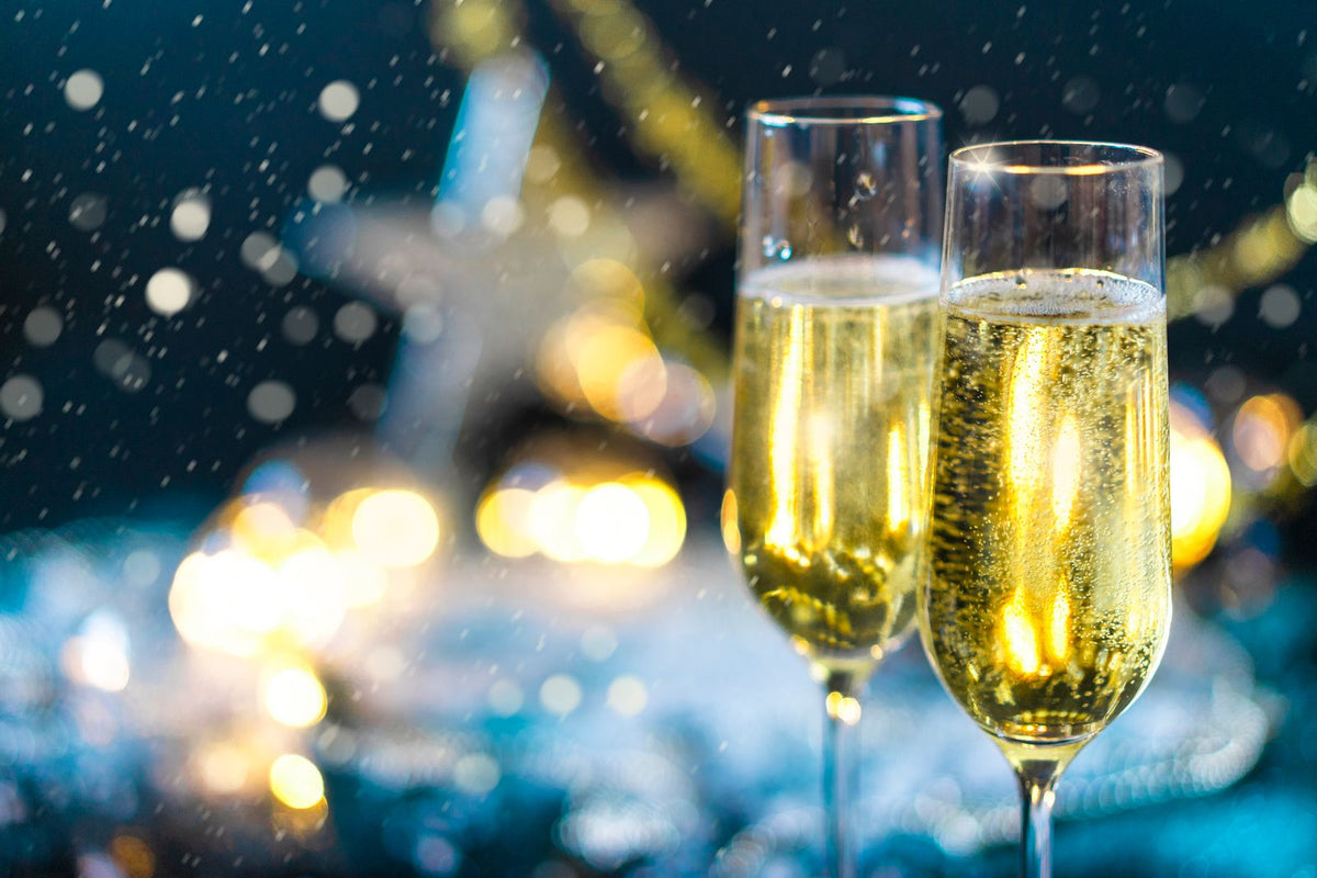 Two champagne flutes filled with sparkling wine against soft lights