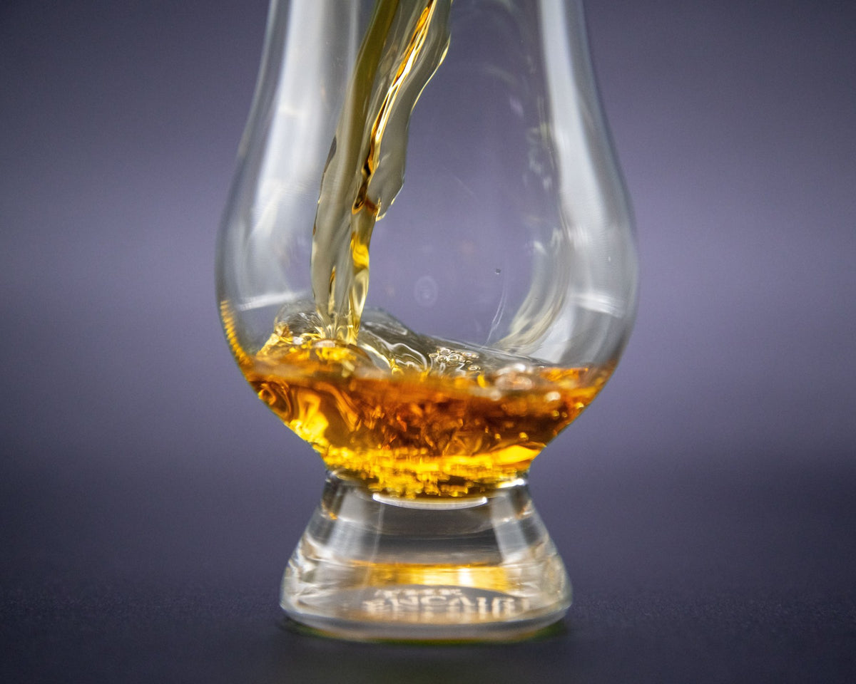 Amber single malt whisky being poured into a tulip-shaped tasting glass
