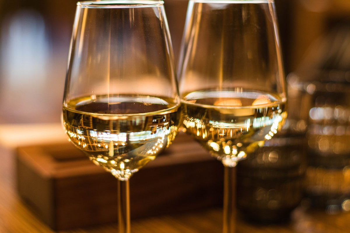 Two glasses of chilled white wine with soft bokeh light in the background