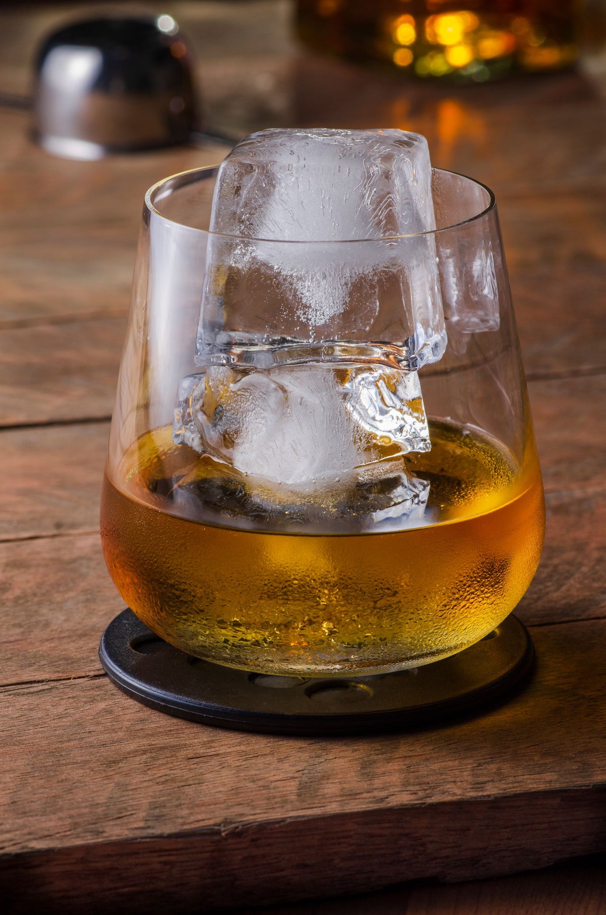 A whiskey glass with large ice cubes on a wooden table