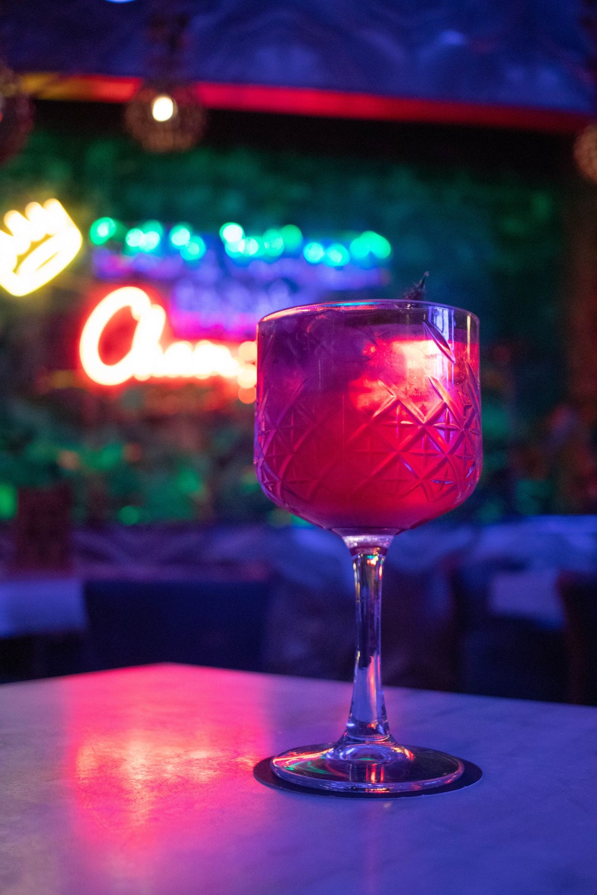 Cocktail served over ice at a neon-lit bar