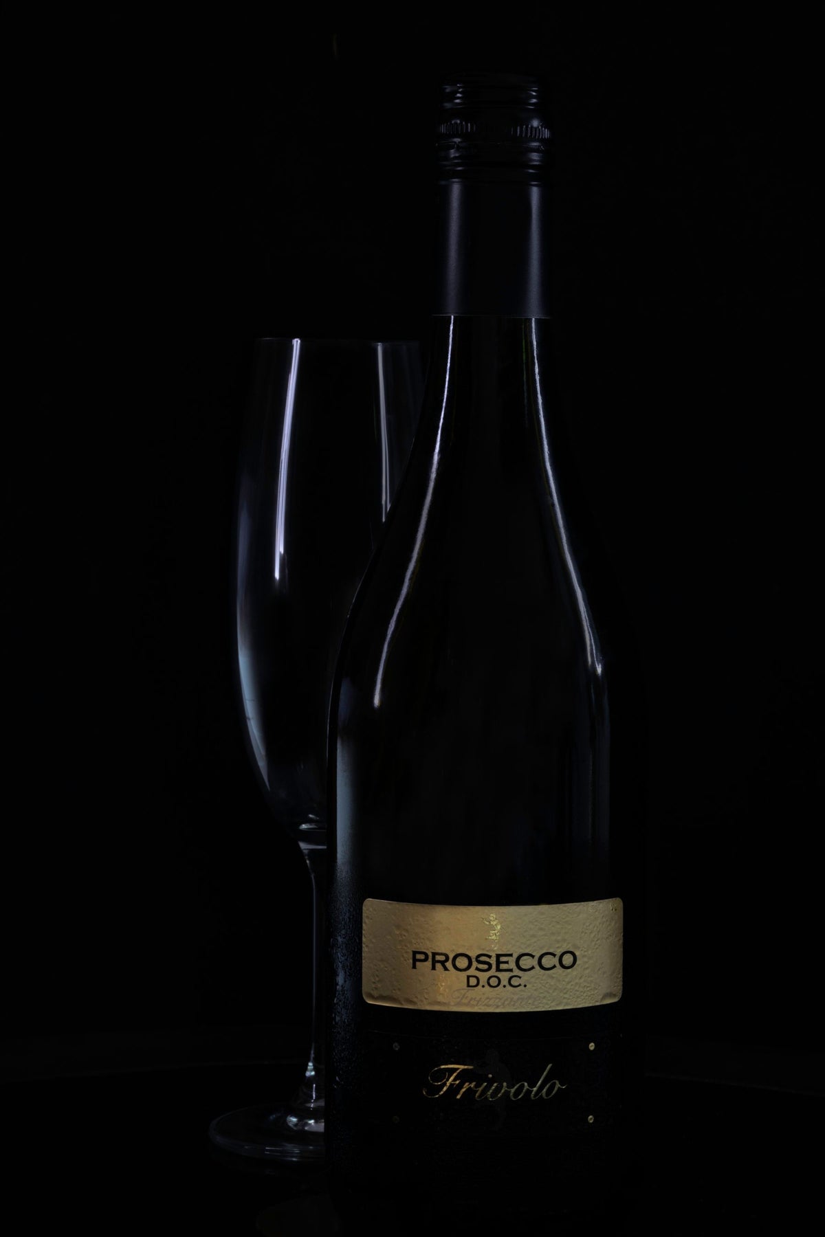 A bottle of Prosecco and a filled flute against a dark background