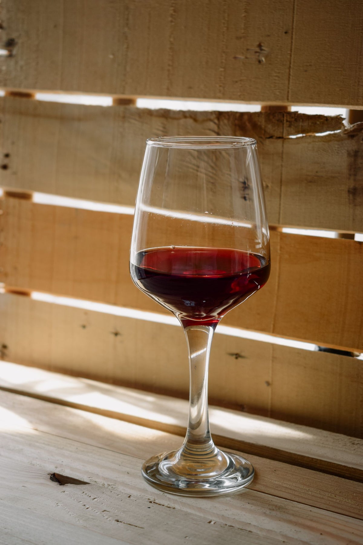A glass of dark red port wine on a wooden table