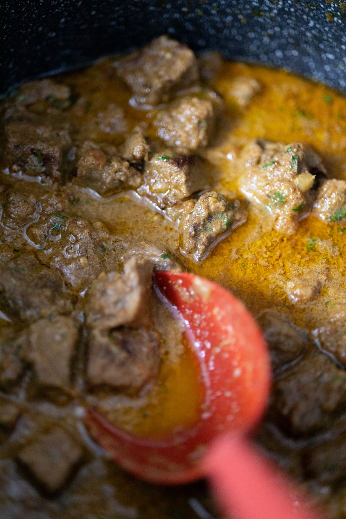 A pot of slow-cooked beef cholent in dark gravy