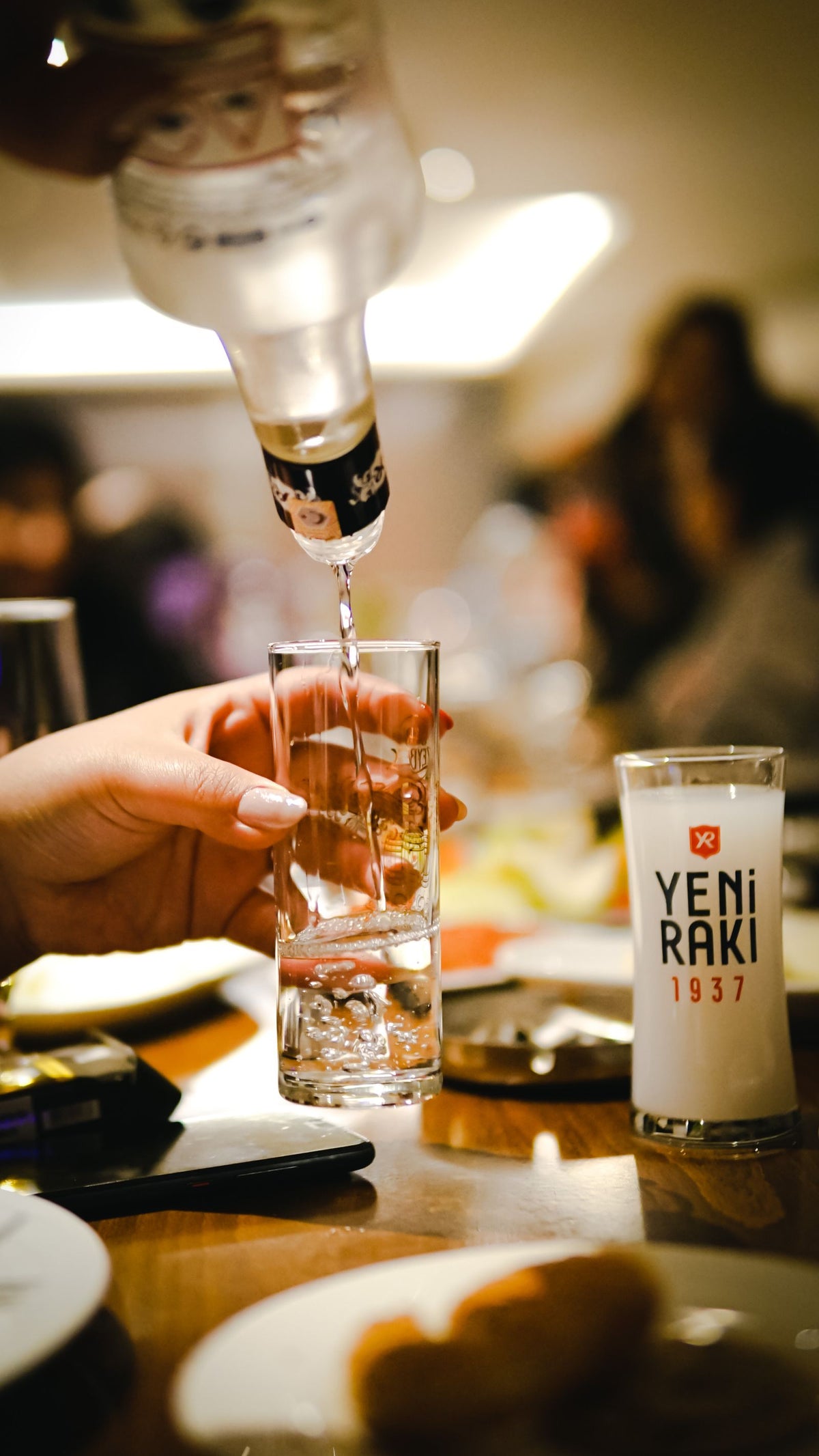 Anise spirit being poured into a glass at a bar