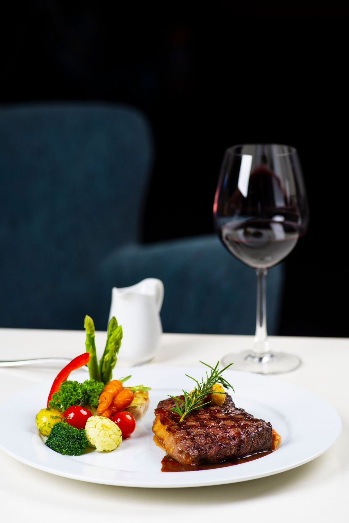A plated steak with vegetables beside a glass of red wine