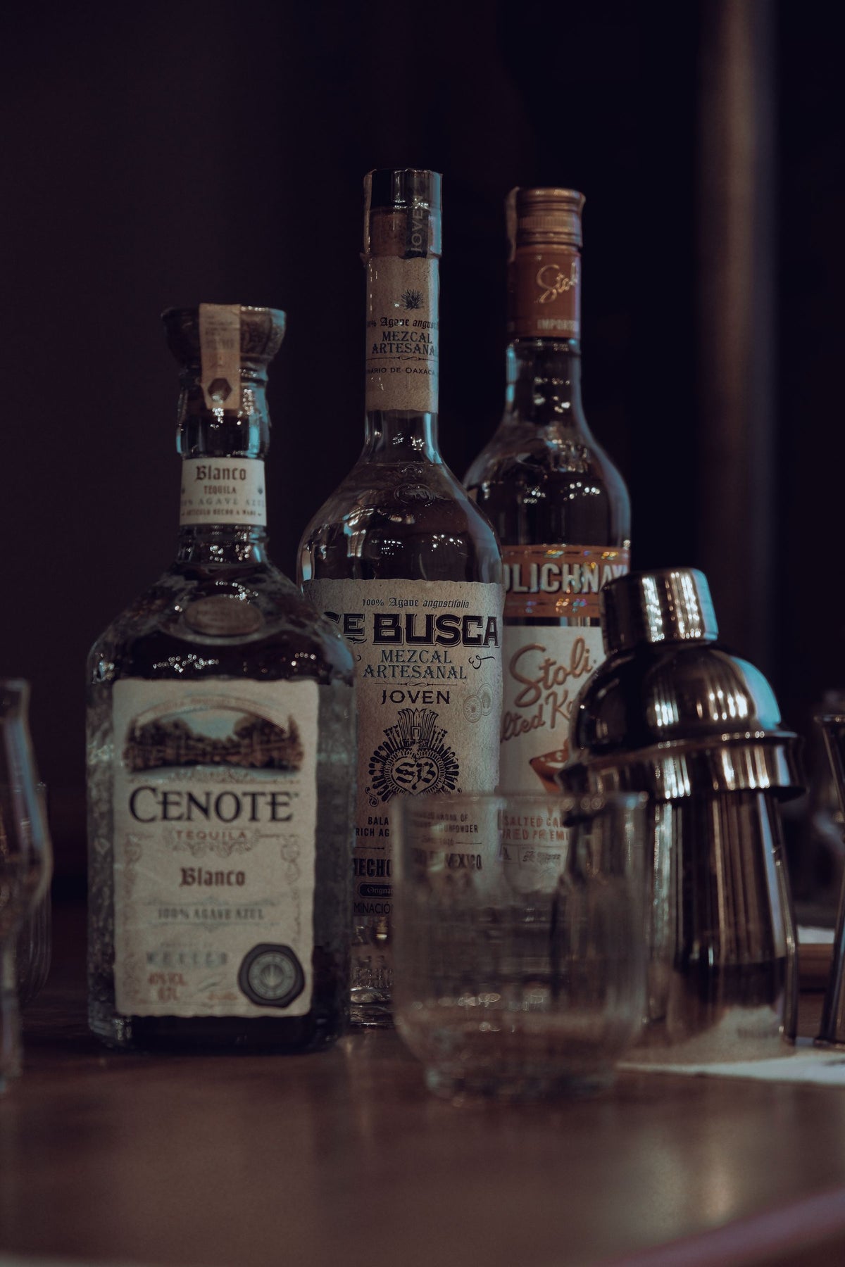 Premium spirit bottles lined up on a wooden bar counter