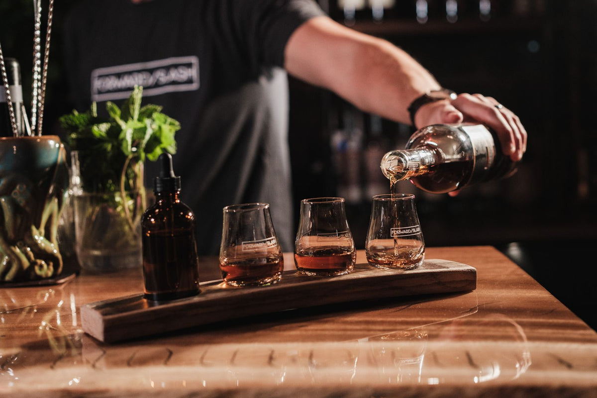 Bartender pouring whiskey samples for a tasting flight