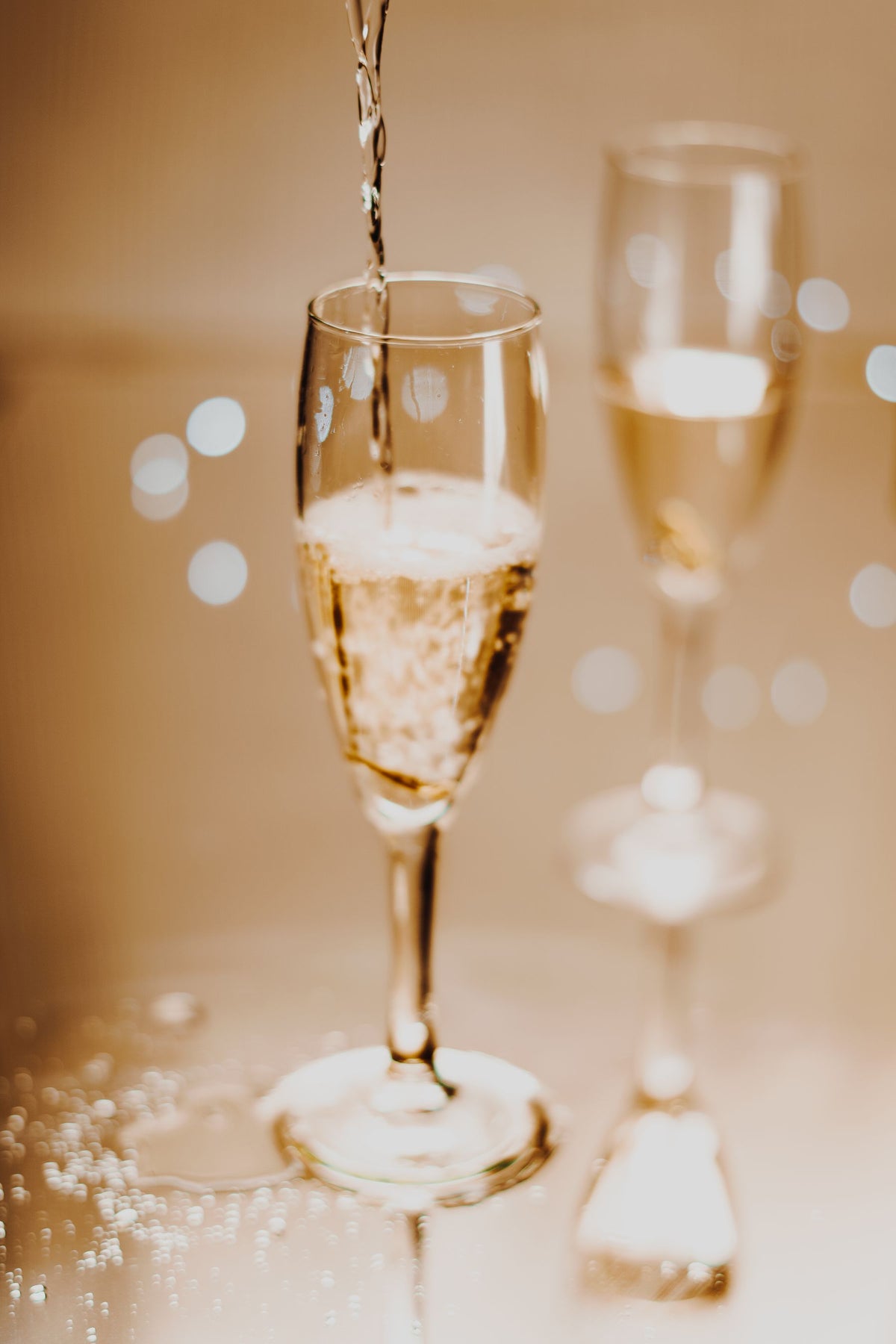 Sparkling wine being poured into a tall flute with a fine stream of bubbles
