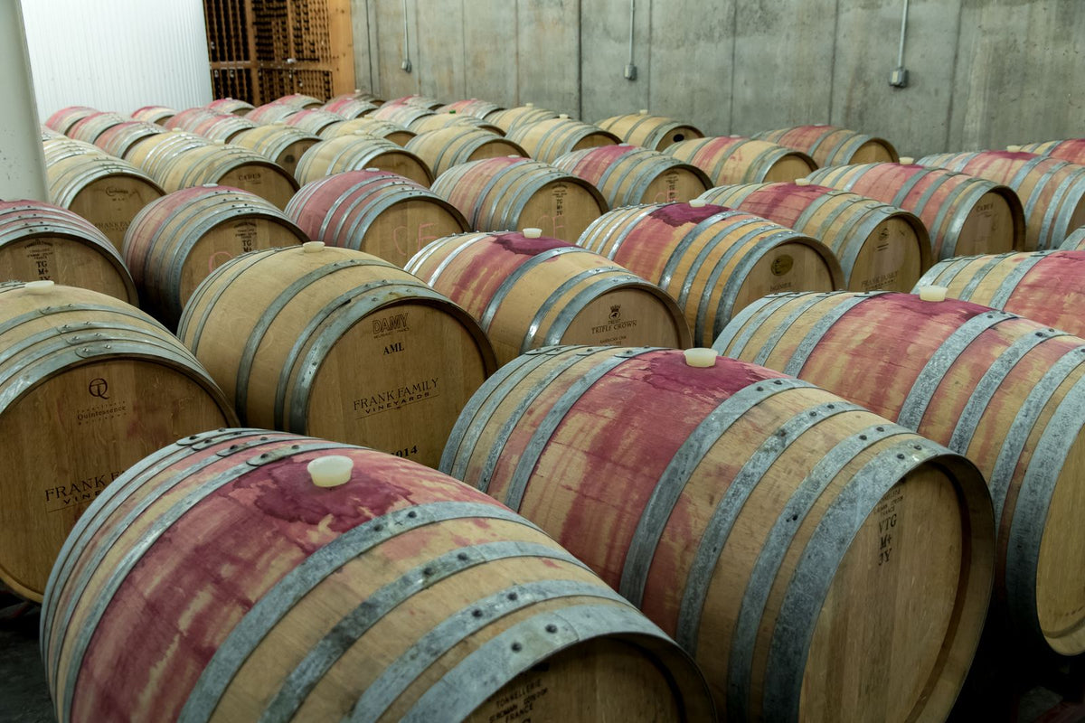 Oak barrels aging wine in a quiet winery cellar