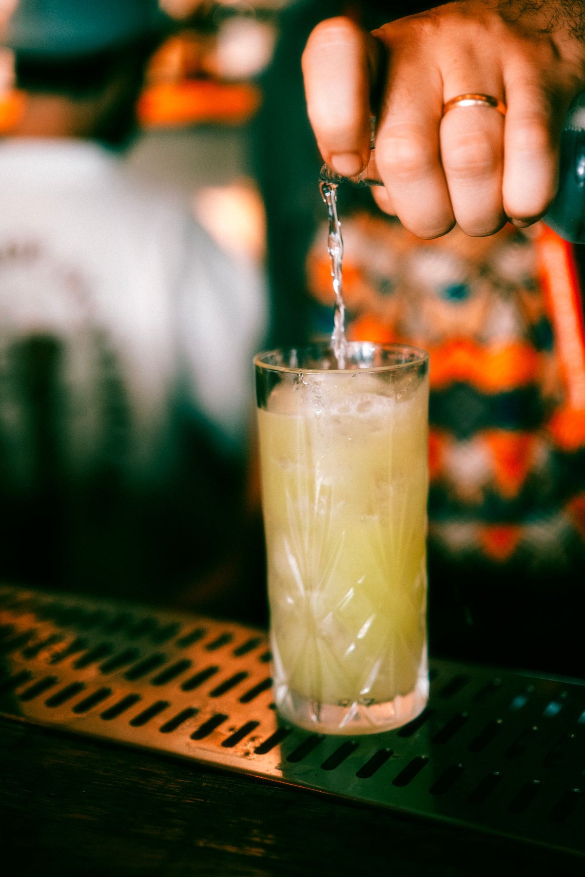 Bartender pouring a premium tequila cocktail at a dim, elegant bar