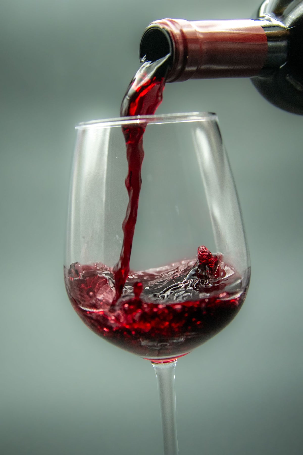 Dark red wine being poured from a bottle into a glass