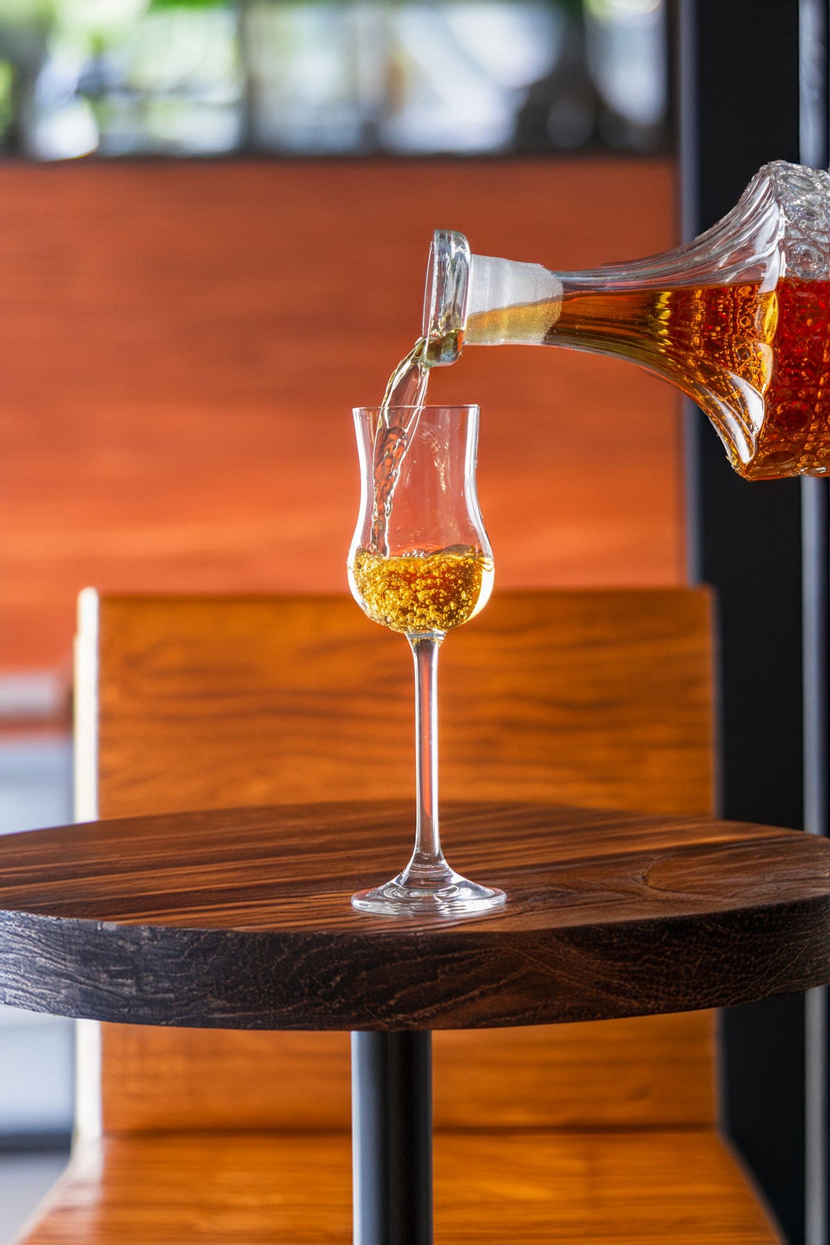 Whisky being poured into a crystal glass on a dark wooden table