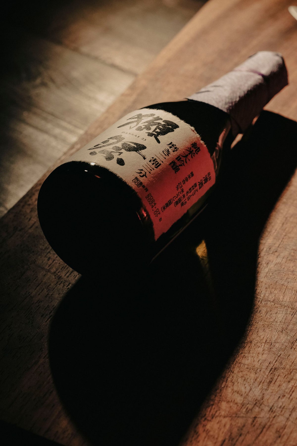 A Japanese sake bottle on a wooden surface in moody low light