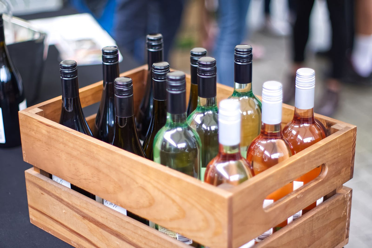 A wooden crate filled with an assortment of wine bottles outdoors