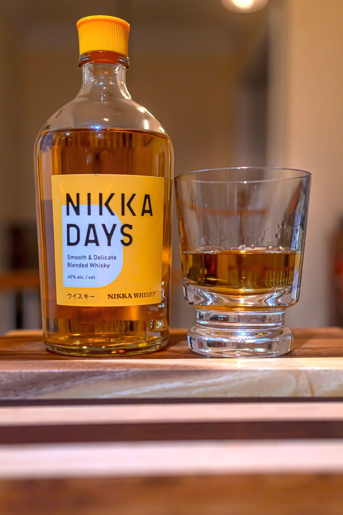 A bottle of Japanese whisky beside a filled glass on a wooden board