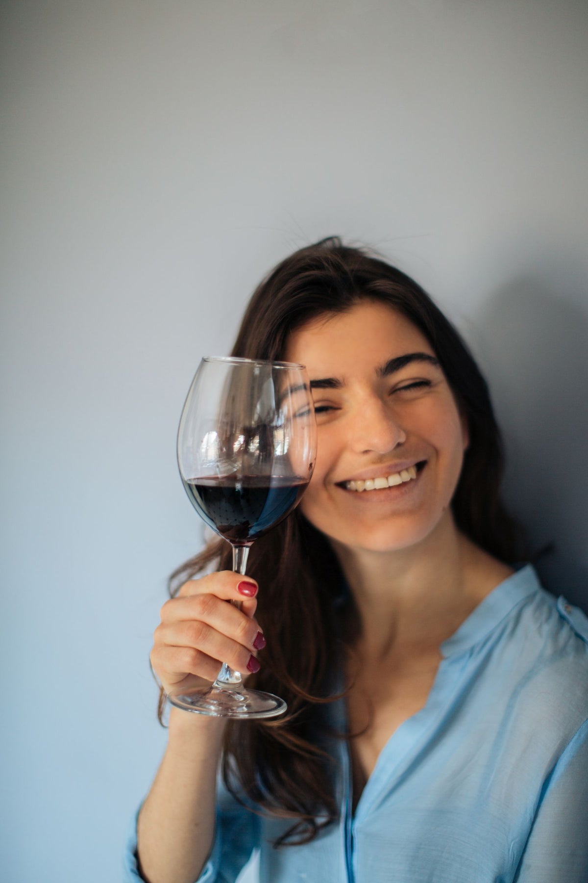 A woman smiling while enjoying a glass of red wine