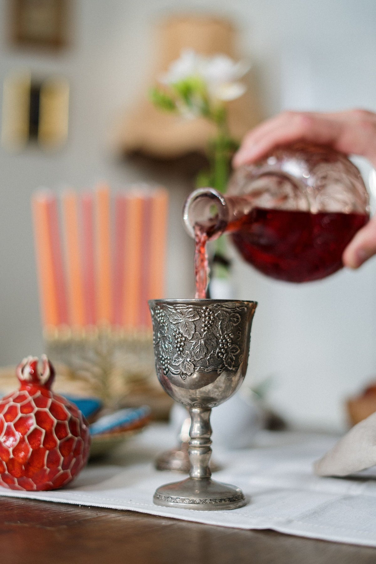 Kiddush cup being filled with sweet kosher wine at a Rosh Hashanah table