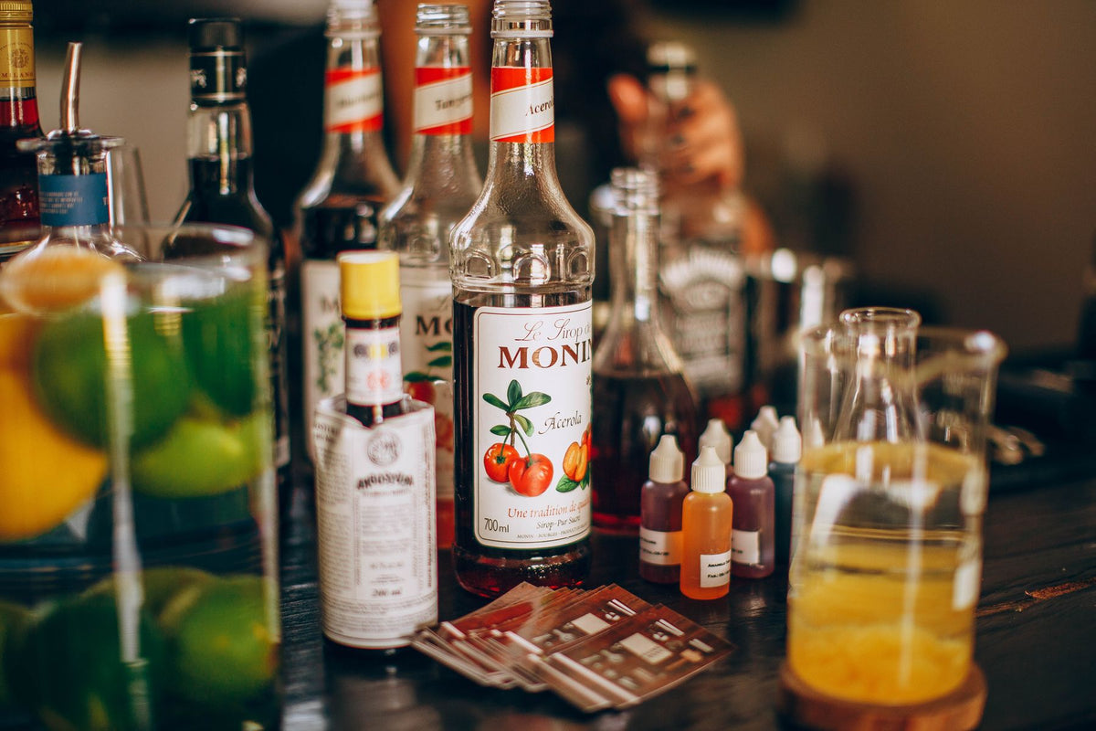 An assortment of cocktail syrup bottles on a bar counter
