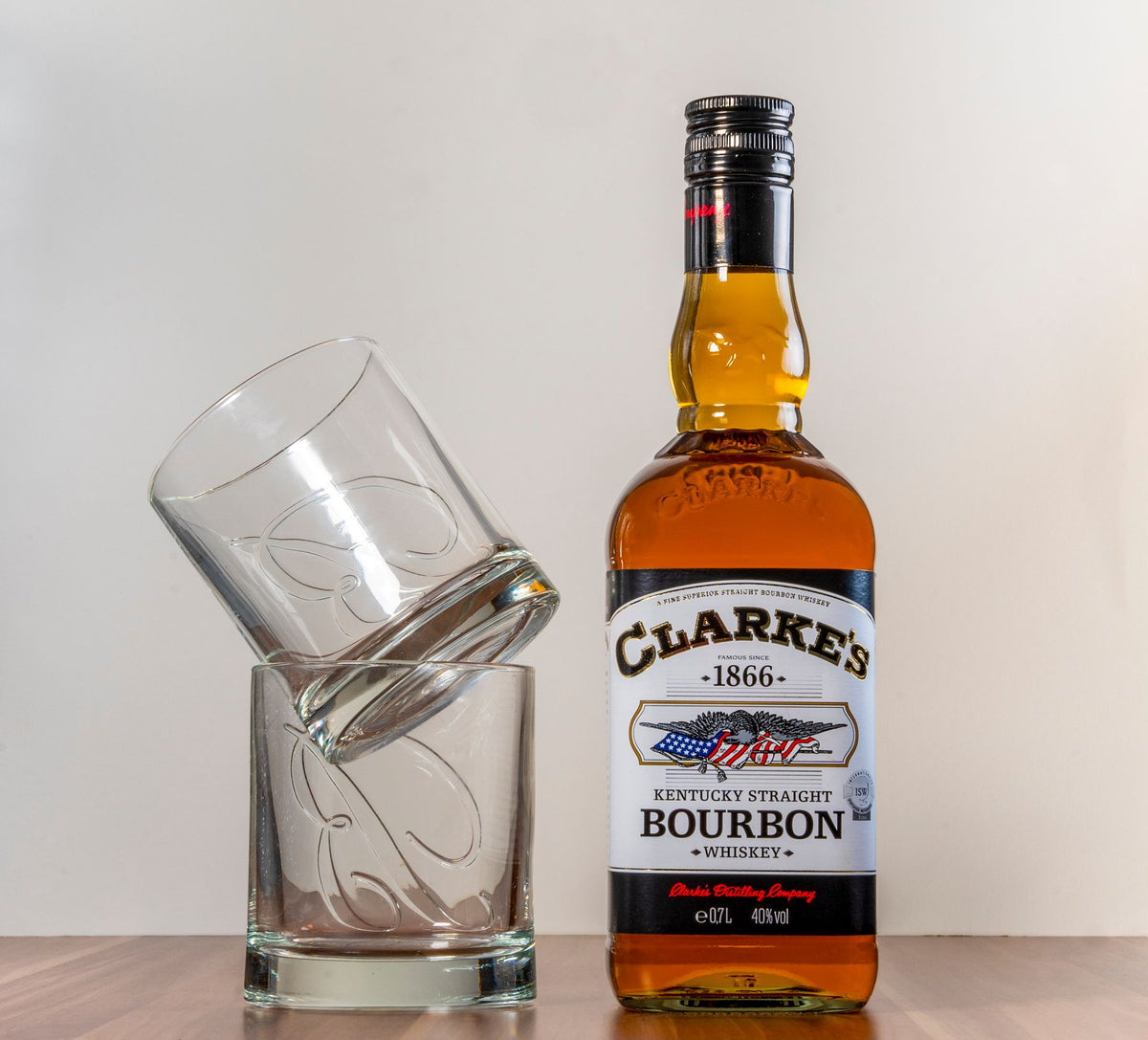 A bottle of bourbon beside tilted glasses on a wooden surface