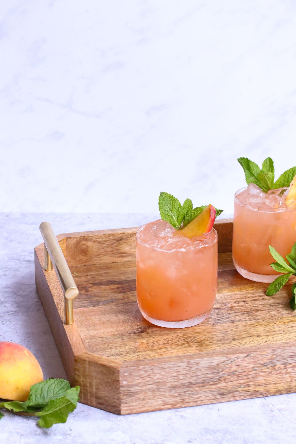 Two tall fruit cocktails with orange garnish on a bar