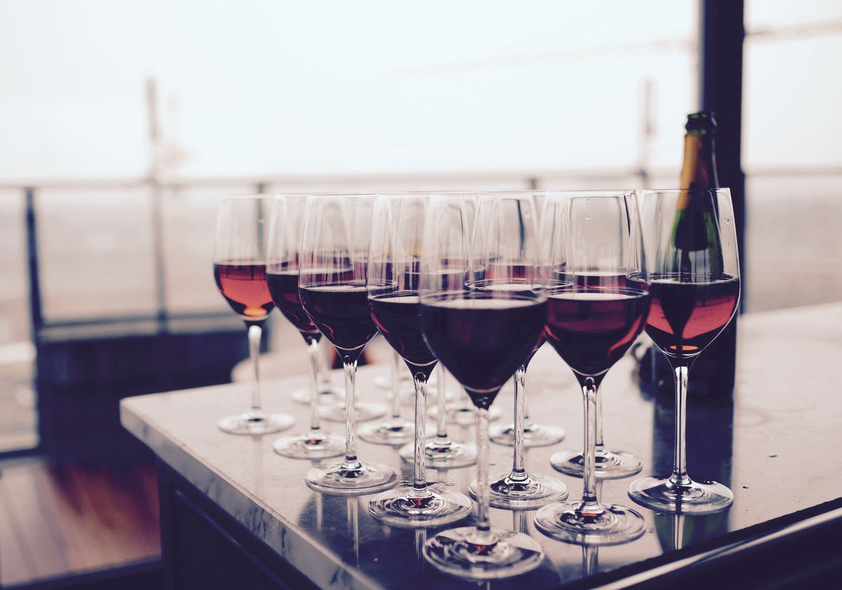 Several glasses of red wine lined up on a bar for a tasting