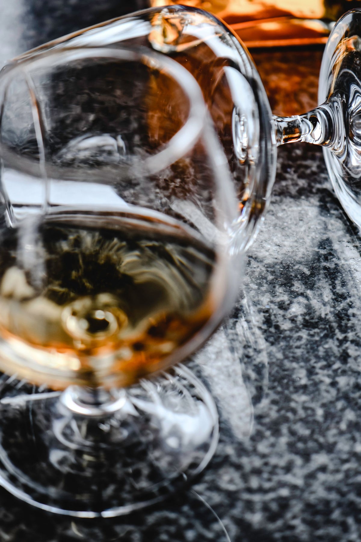Two glasses of amber brandy on a granite counter