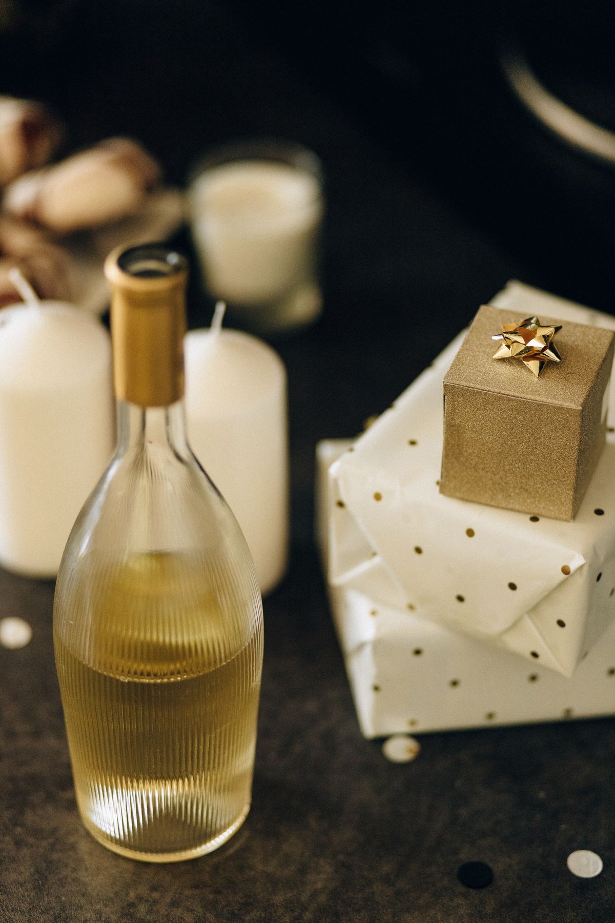 An elegantly wrapped wine gift beside glowing candles
