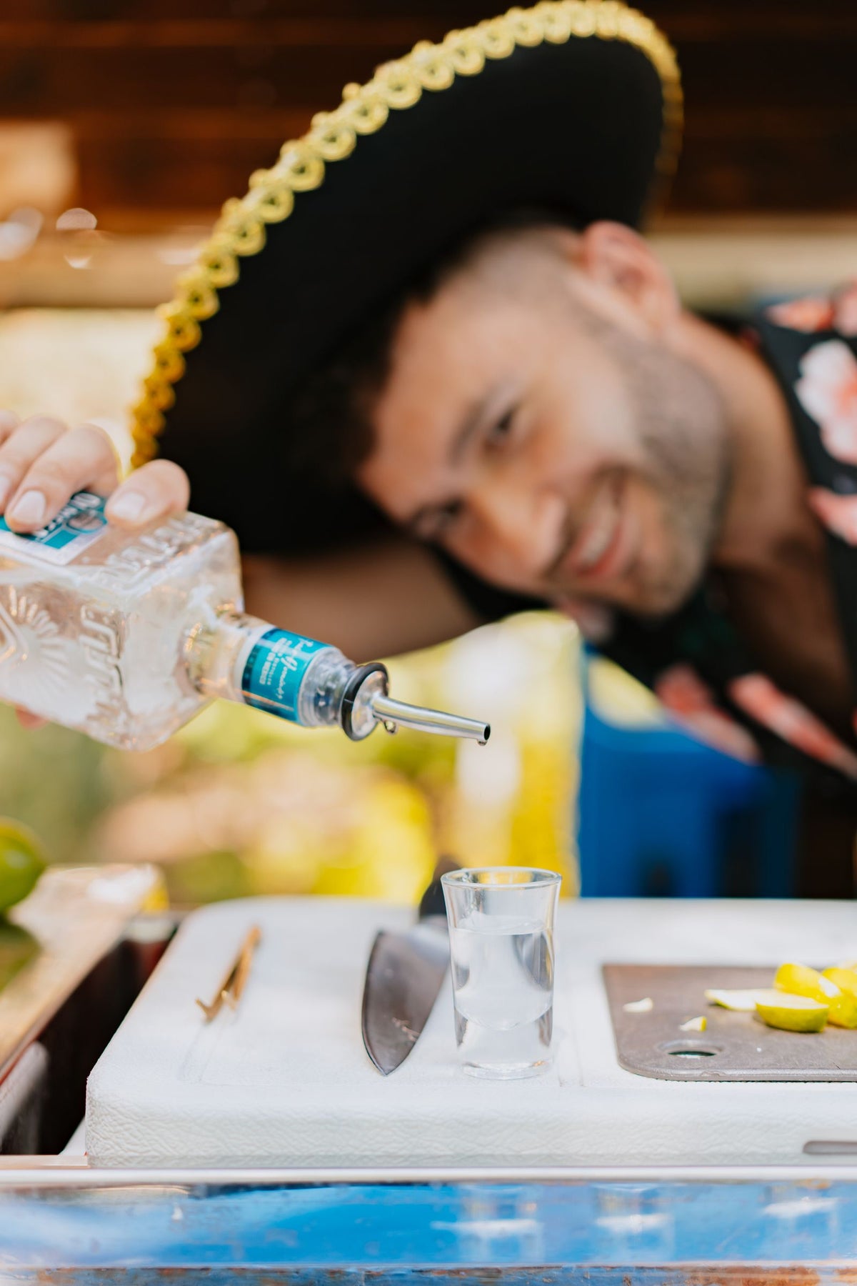 Bartender pouring a tequila shot with fresh lime at a lively bar