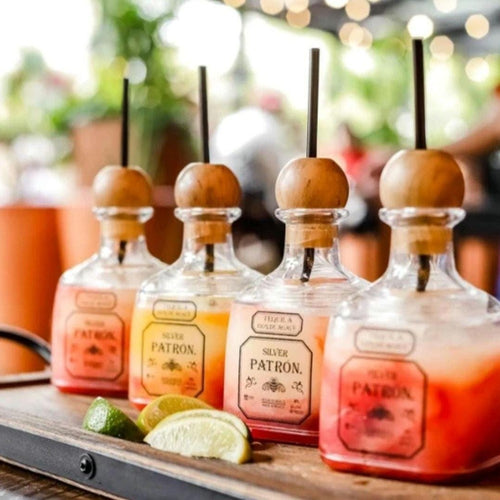 Patron replica plastic bottles filled with cocktails and straws at a party